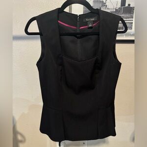 Black sleeveless top with a zipper and clip.
Ruffle accent
